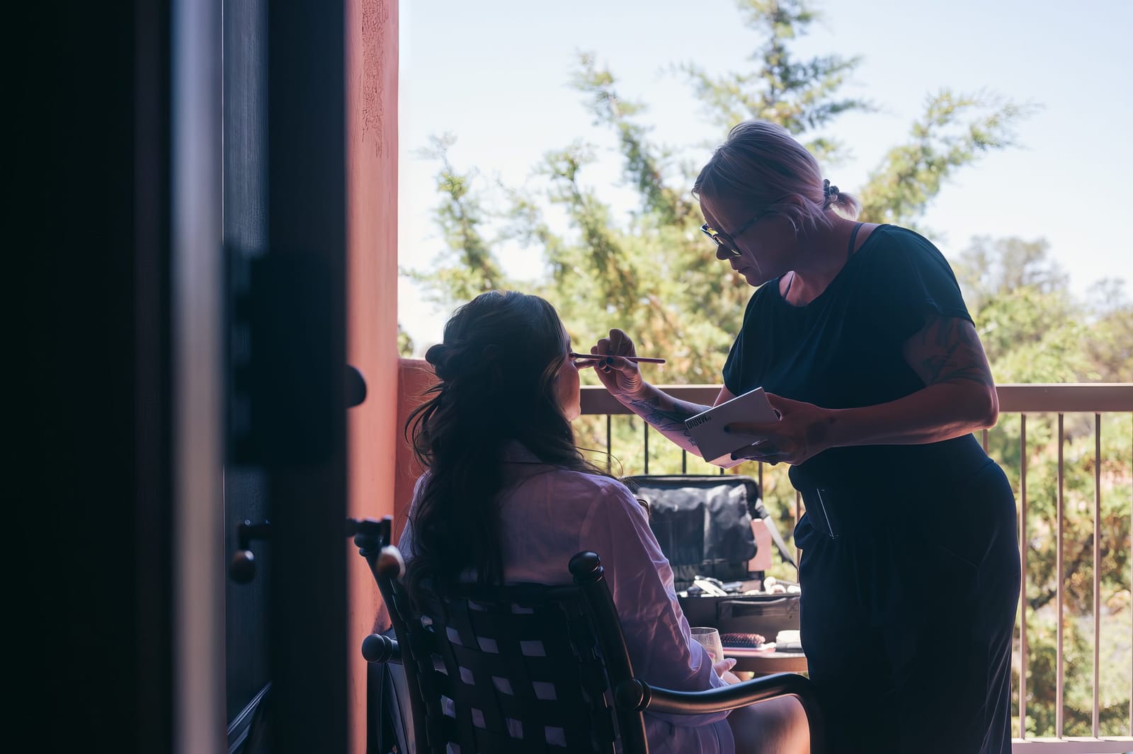 Dina having her makeup done on a sunlit balcony
